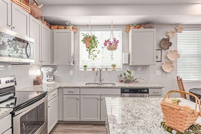 4790 Kittredge St, Denver, CO 80239 - kitchen featuring stainless steel appliances, decorative backsplash, light wood-style flooring, and light stone counters