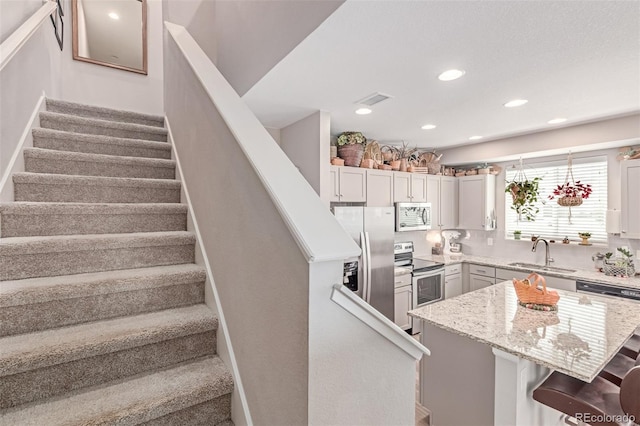 4790 Kittredge St, Denver, CO 80239 - kitchen with stainless steel appliances, a breakfast bar area, a kitchen island, light stone counters, and recessed lighting