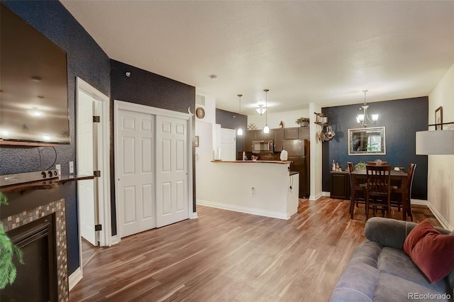 2430 W 82nd Pl Unit 2F, Westminster, CO 80031 - living area with wood finished floors, a tiled fireplace, baseboards, and a chandelier