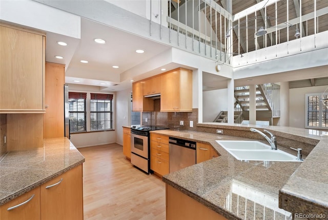 kitchen with light wood finished floors, decorative backsplash, recessed lighting, appliances with stainless steel finishes, and a sink