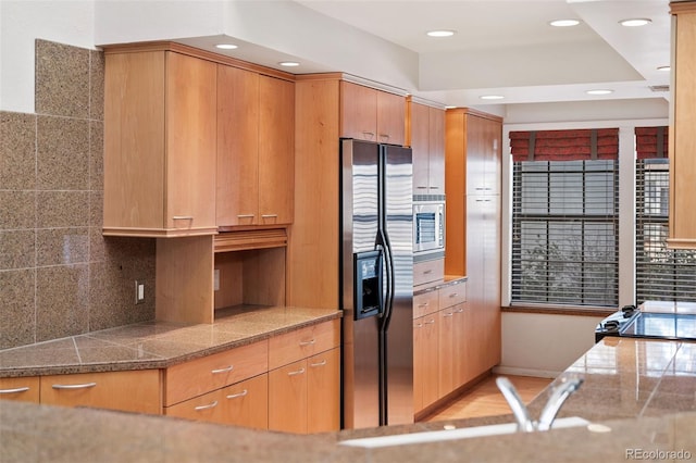 kitchen featuring tile countertops, recessed lighting, a sink, stainless steel appliances, and backsplash