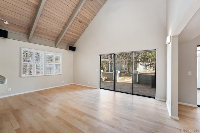 empty room featuring beamed ceiling, baseboards, and wood finished floors