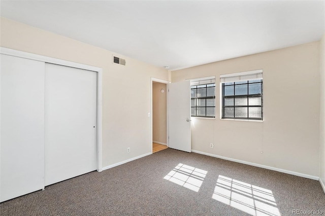 unfurnished bedroom featuring visible vents, carpet floors, baseboards, and a closet