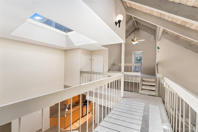 hall featuring beam ceiling, an upstairs landing, wooden ceiling, and carpet floors