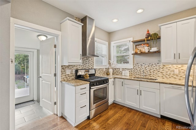 3881 Zenobia St, Denver, CO 80212 - kitchen featuring stainless steel range with gas stovetop, wall chimney exhaust hood, white cabinetry, decorative backsplash, and light stone countertops