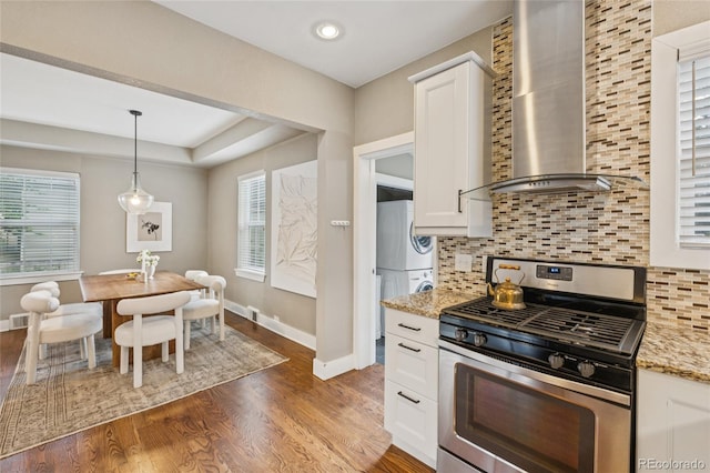 3881 Zenobia St, Denver, CO 80212 - kitchen with stainless steel gas range oven, wall chimney range hood, estacked washer and dryer, healthy amount of natural light, and recessed lighting