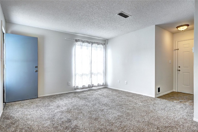 unfurnished room with carpet floors, a textured ceiling, visible vents, and baseboards