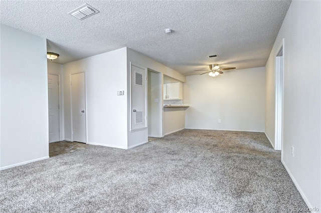 unfurnished living room with visible vents, carpet flooring, baseboards, and a ceiling fan