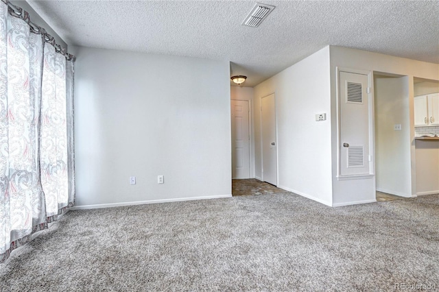 spare room featuring carpet floors, a textured ceiling, and visible vents
