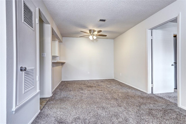 unfurnished living room with a textured ceiling, carpet, a ceiling fan, baseboards, and visible vents