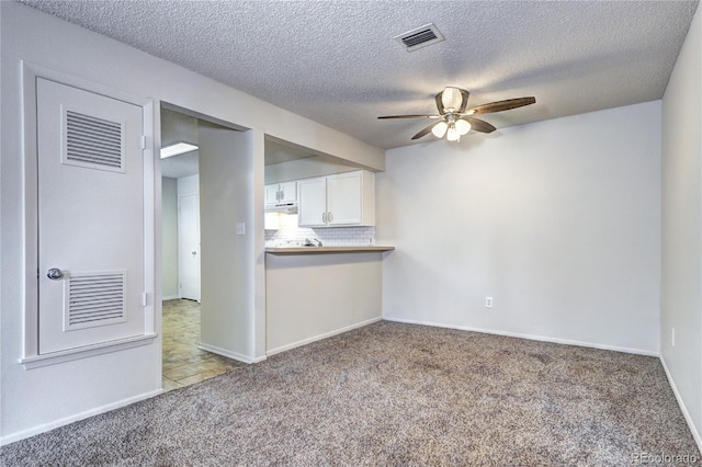 interior space featuring carpet floors, ceiling fan, a textured ceiling, and visible vents