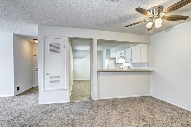 kitchen with ceiling fan, visible vents, freestanding refrigerator, carpet, and white cabinetry