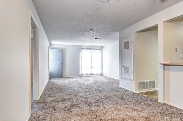 carpeted empty room with baseboards, a textured ceiling, and visible vents