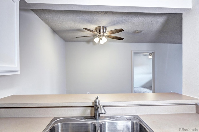 kitchen featuring ceiling fan, visible vents, a sink, light countertops, and white cabinets