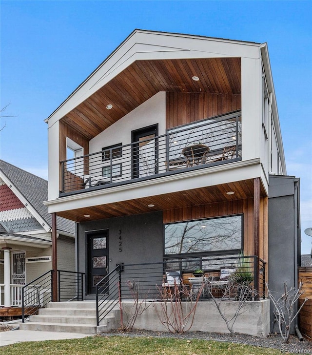 modern home featuring a porch, a balcony, and stucco siding