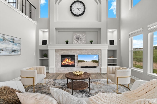 3041 Starling Ct, Castle Rock, CO 80109 - living area with a towering ceiling, built in features, wood finished floors, plenty of natural light, and a stone fireplace