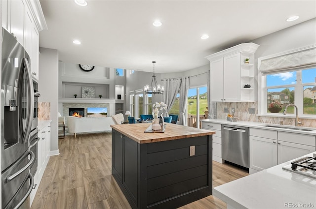 3041 Starling Ct, Castle Rock, CO 80109 - kitchen with stainless steel appliances, wooden counters, a sink, white cabinets, and a kitchen island