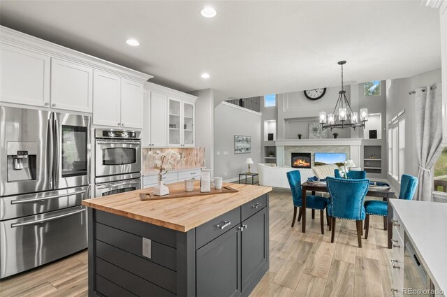 3041 Starling Ct, Castle Rock, CO 80109 - kitchen featuring stainless steel appliances, butcher block countertops, white cabinets, decorative backsplash, and light wood finished floors