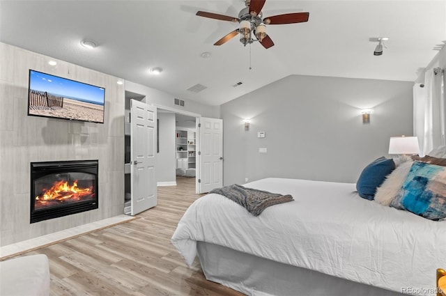 3041 Starling Ct, Castle Rock, CO 80109 - bedroom with lofted ceiling, light wood-style floors, a tiled fireplace, and ceiling fan