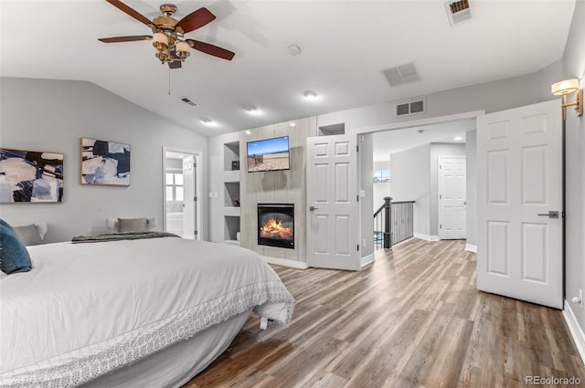 3041 Starling Ct, Castle Rock, CO 80109 - bedroom featuring wood finished floors, baseboards, vaulted ceiling, connected bathroom, and a tile fireplace