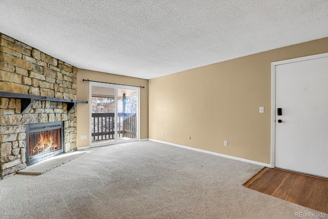 unfurnished living room featuring carpet, a textured ceiling, and a stone fireplace