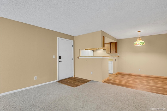 interior space with a textured ceiling, white refrigerator, light colored carpet, and hanging light fixtures