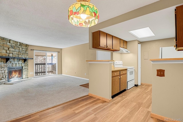 kitchen with light carpet, a textured ceiling, white appliances, decorative light fixtures, and a stone fireplace