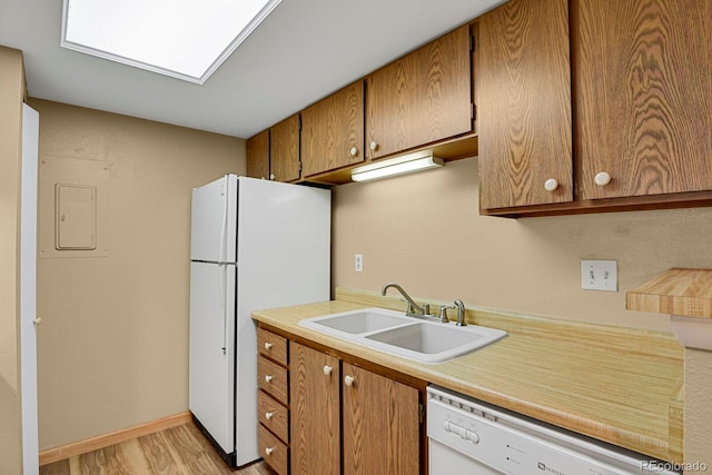 kitchen with white appliances, sink, electric panel, and light hardwood / wood-style flooring