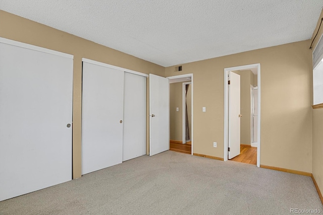 unfurnished bedroom featuring light colored carpet, a textured ceiling, and a closet