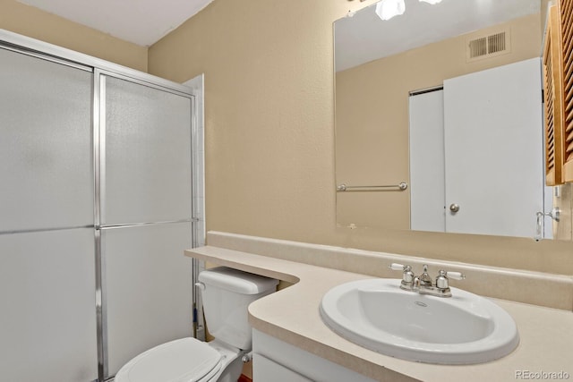 bathroom featuring vanity, toilet, and a shower with shower door