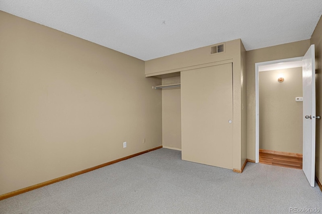 unfurnished bedroom with light carpet, a closet, and a textured ceiling