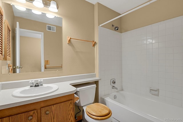 full bathroom with tiled shower / bath, vanity, and toilet