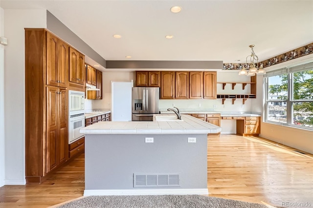 2561 Cactus Bluff Pl, Highlands Ranch, CO 80129 - kitchen featuring white appliances, open shelves, light wood finished floors, a chandelier, and under cabinet range hood