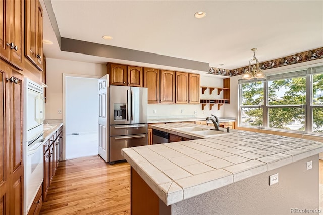 2561 Cactus Bluff Pl, Highlands Ranch, CO 80129 - kitchen with stainless steel fridge, tile counters, light wood-style floors, brown cabinetry, and open shelves