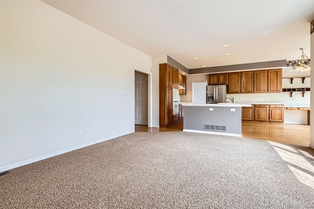 2561 Cactus Bluff Pl, Highlands Ranch, CO 80129 - kitchen featuring carpet floors, stainless steel fridge with ice dispenser, light countertops, open floor plan, and a chandelier