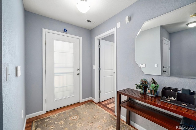interior space featuring baseboards, wood finished floors, and visible vents