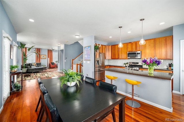 dining space with dark wood-type flooring, baseboards, recessed lighting, and stairs
