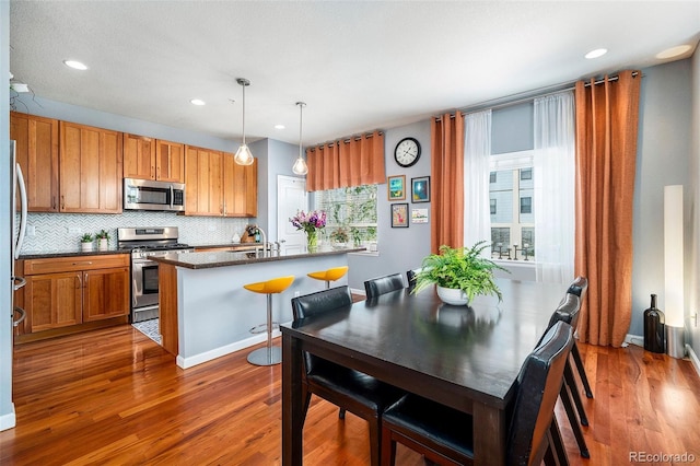 kitchen featuring recessed lighting, stainless steel appliances, backsplash, wood finished floors, and a sink