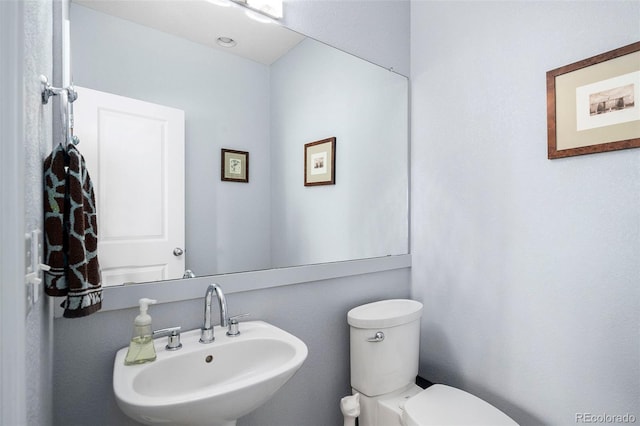 half bath featuring toilet and a sink
