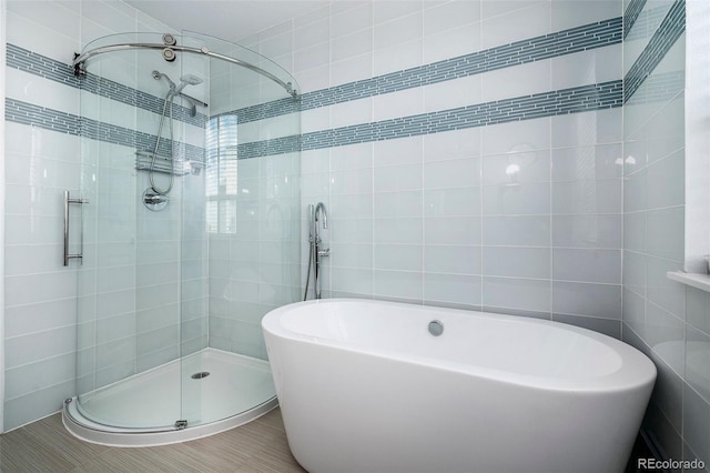 bathroom with tile walls, a freestanding tub, and a stall shower