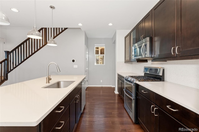 kitchen featuring decorative light fixtures, stainless steel appliances, tasteful backsplash, sink, and a kitchen island with sink