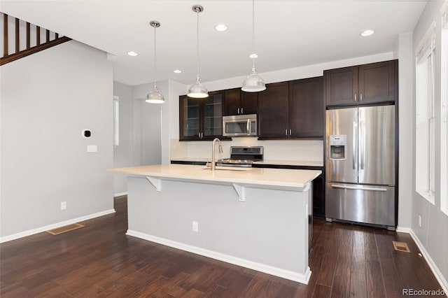 kitchen featuring sink, appliances with stainless steel finishes, an island with sink, and dark brown cabinets