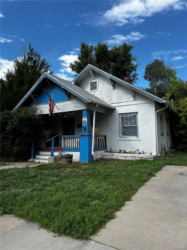 710 Carson St, Brush, CO 80723 - bungalow-style home featuring a porch, a front lawn, brick siding, and a chimney