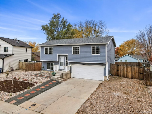 split foyer home featuring concrete driveway, fence, and an attached garage