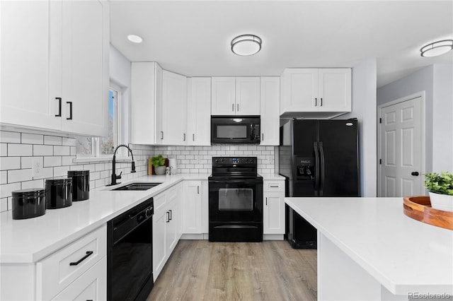 kitchen with light countertops, decorative backsplash, white cabinetry, a sink, and black appliances