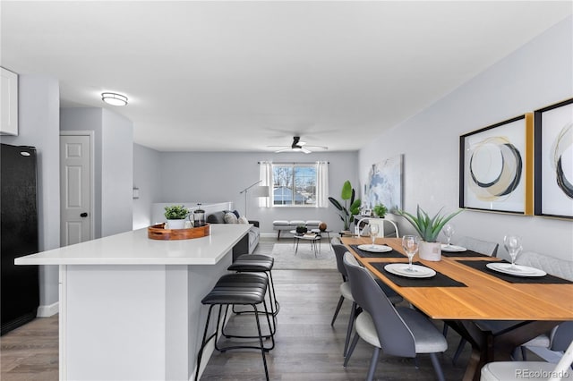 dining space with light wood finished floors, baseboards, and a ceiling fan