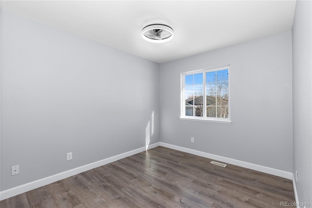 empty room with dark wood-style floors, baseboards, and visible vents