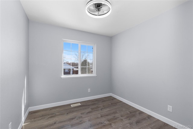 spare room featuring visible vents, baseboards, and dark wood-style flooring