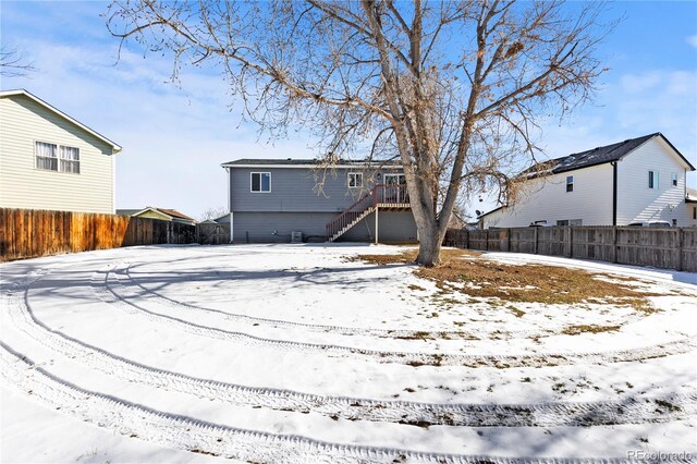 snow covered back of property with stairway and fence