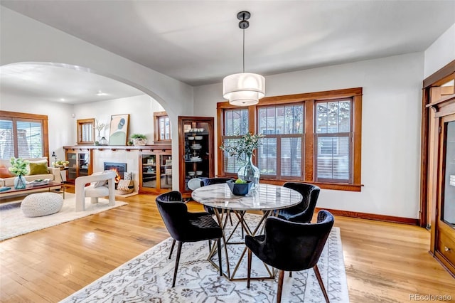 285 S Williams St, Denver, CO 80209 - dining area featuring baseboards, light wood-type flooring, arched walkways, and a glass covered fireplace